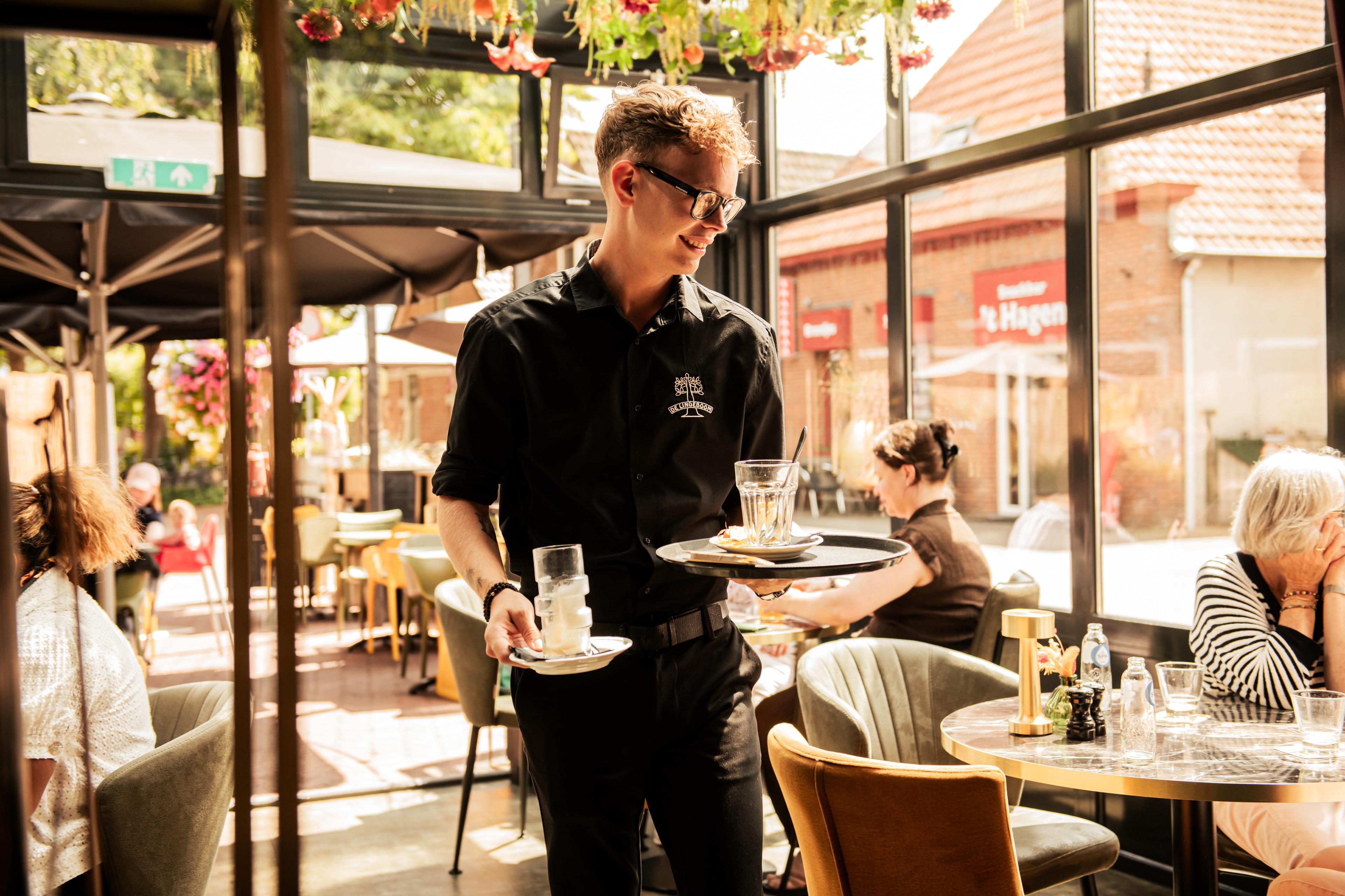 Ober van De Lindeboom serveert drankjes op het terras