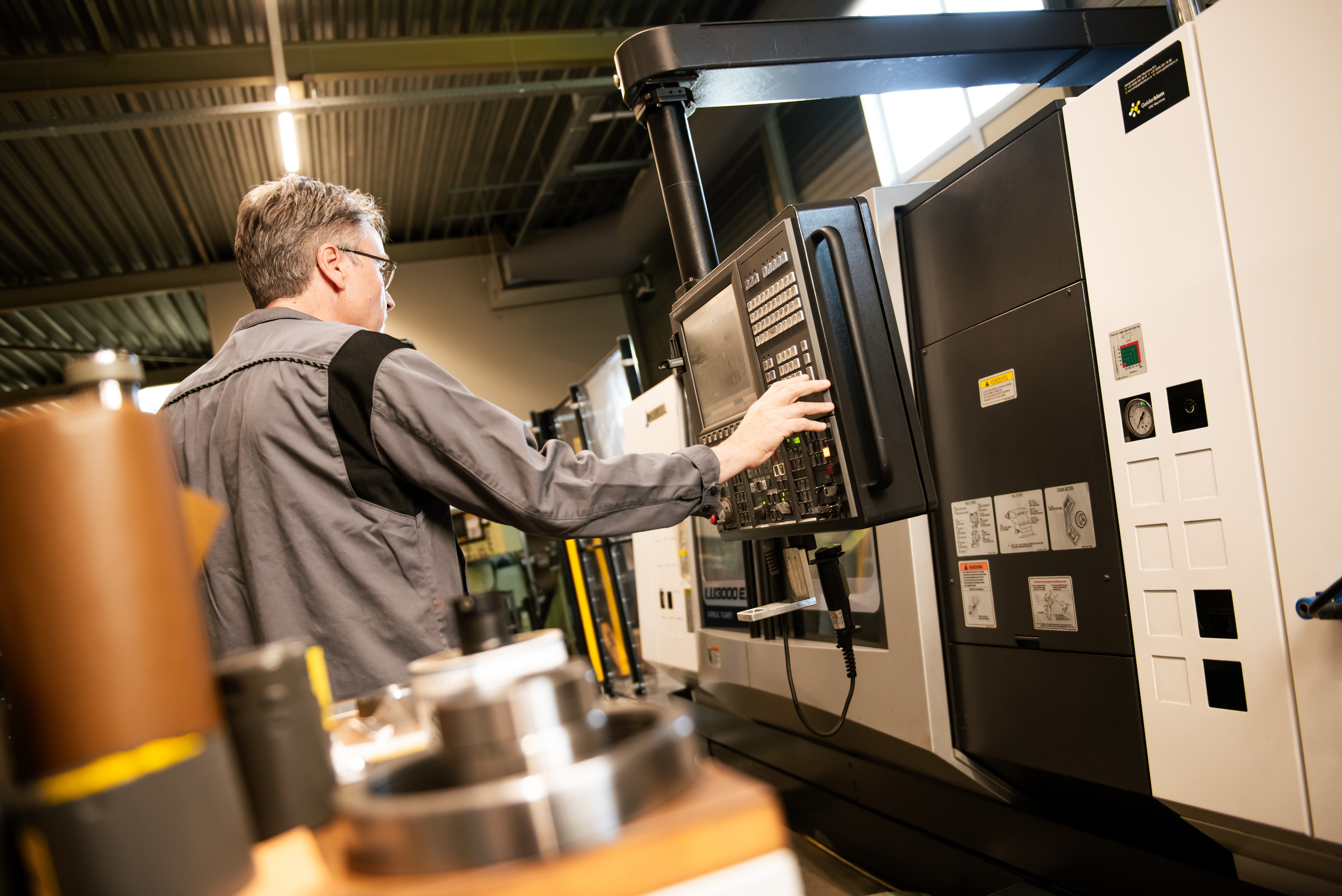 Medewerker van Wissink Metaal bedient een CNC-draaibank