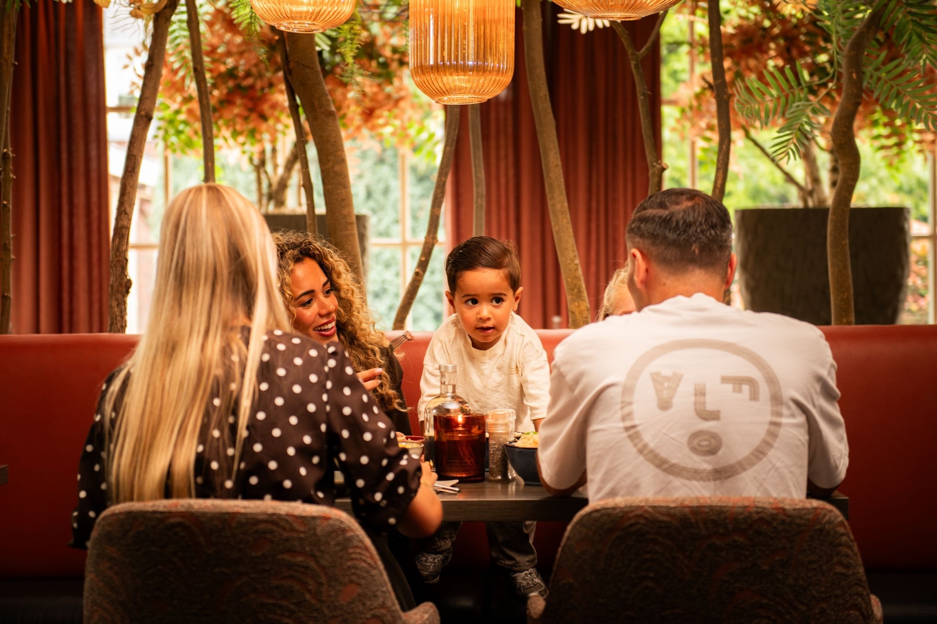 Gezin aan tafel bij Grand Plaza, met een peuter die aan het gesprek meedoet